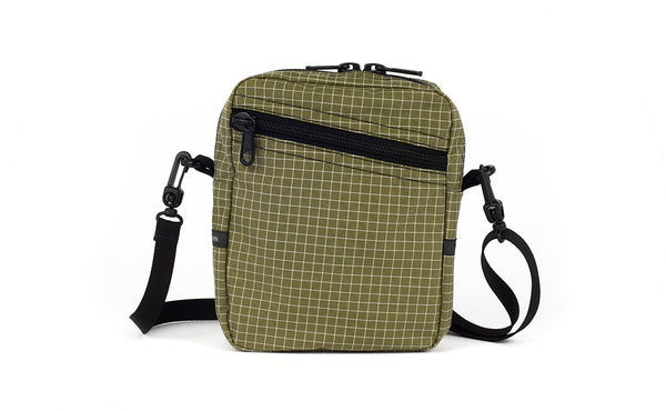 An Everyday Cubelet in Taiga Halcyon (olive green with a white grid) with a front zipper.